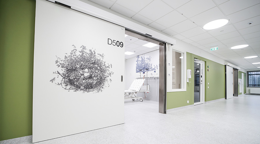 Sairaala Novan vastaanottohuone näkyy avoimesta liukuovessa, jossa on mustavalkoista taidetta.