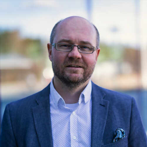 Suonenjoen kaupunginjohtaja Juha Piiroinen auringossa lasiseinää vasten.