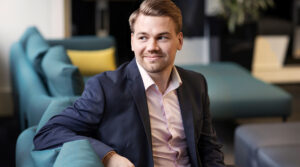 Vastuullisuusanalyytikko Mikko Noronen istumassa sohvalla hymyillen