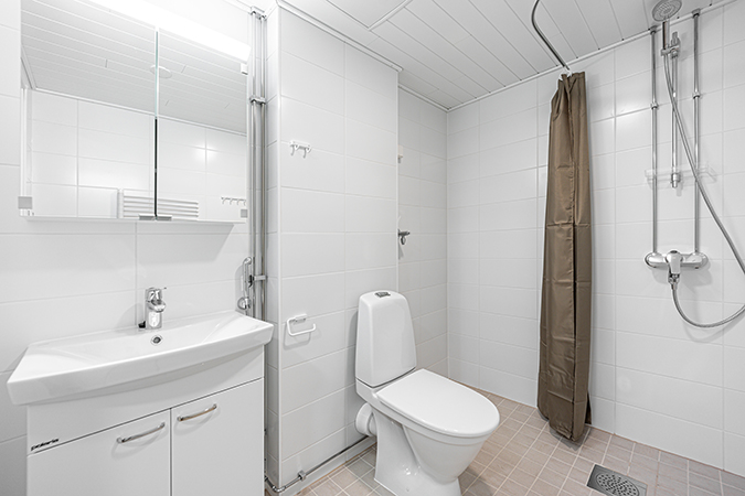 Tilava kylpyhuone, jonka seinät valkoista kaakelia