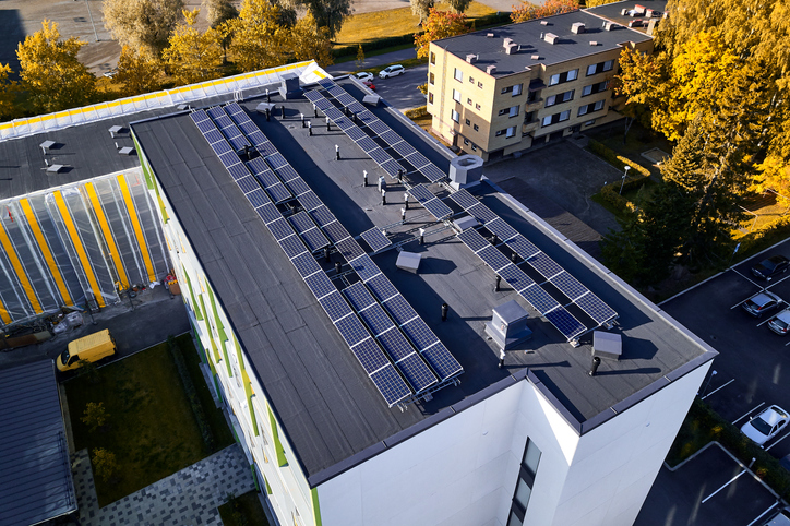 Kuvituskuva, jossa modernin kerrostalon katolle on asennettu aurinkopaneeleja.