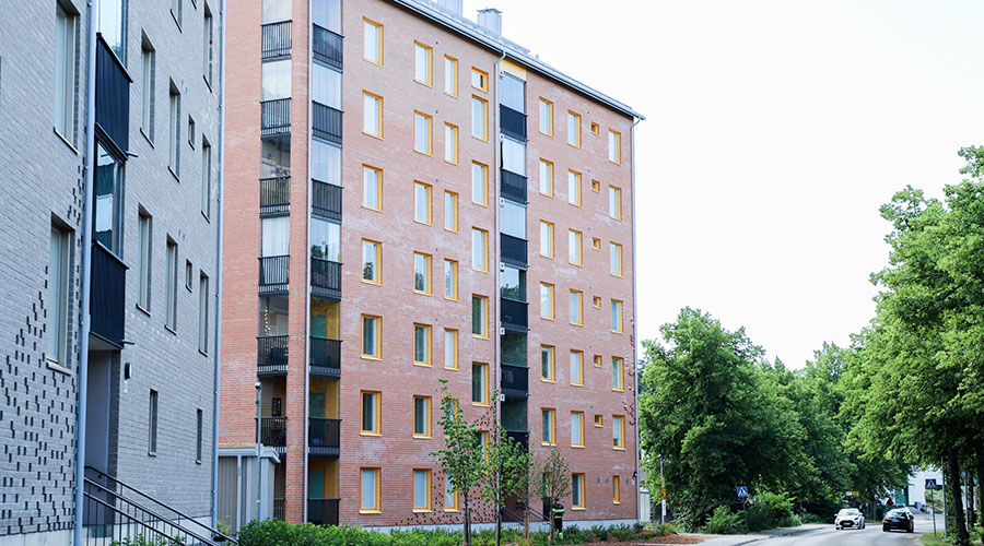 Mäntymäen harmaa- ja punatiilisten 7-kerroksisten talojen julkisivut läheltä kuvattuna kesällä.