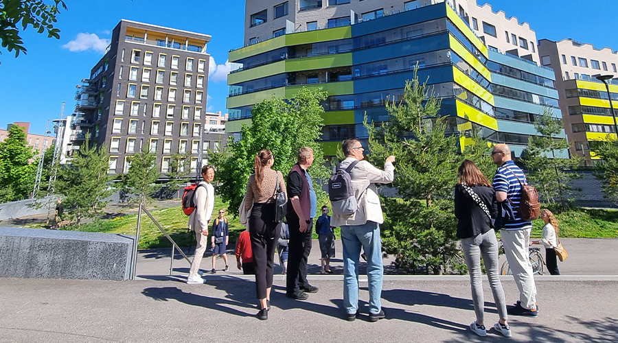 A picture from the ISHF walking tour in Jätkäsaari, Helsinki: a tour group looking at aparment buildings in Jätkäsaari.