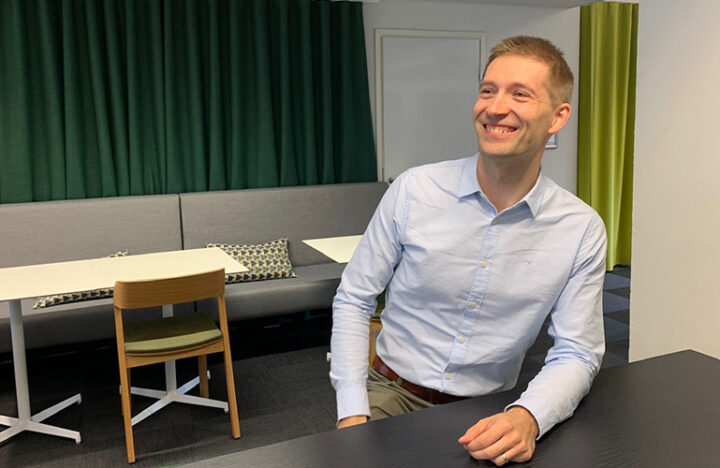 Kuva digitaalisten palveluiden asiantuntija Okko Rostedtista istumassa ja nauramassa pöydän ääressä