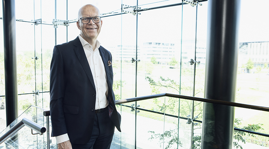 Hymyilevä Esa Kallio lasiseinän vieressä kuvattuna