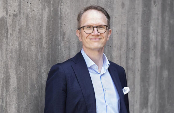 Timo Vesala harmaan betoniseinän edessä kuvattuna.