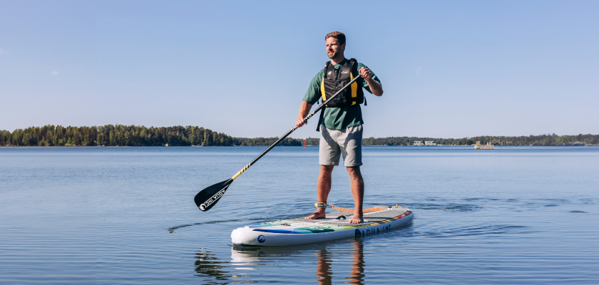 Ihminen meloo sup-laudalla suomalaisessa merimaisemassa.