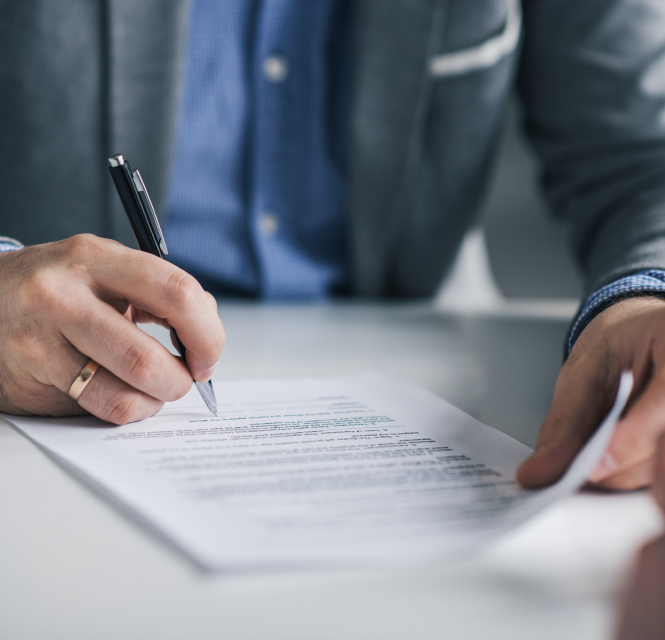 A person's hands signing a paper.