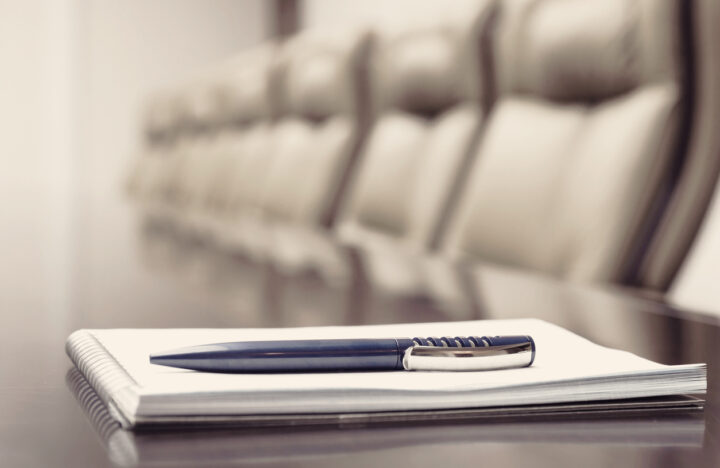 Closeup of notepad kept on table in empty conference room