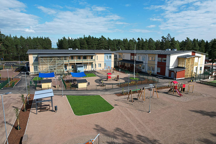 Koulu, päiväkoti ja niiden edustalla piha leikkipaikkoineen