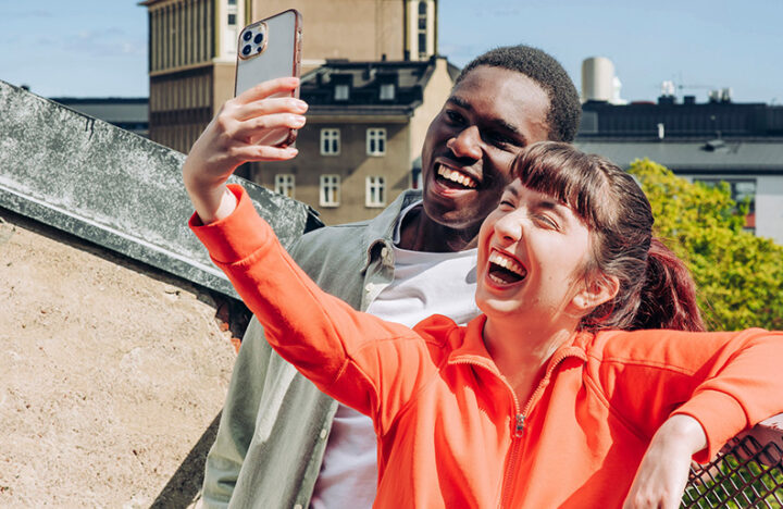 Kuvassa on kaksi nuorta suomalaisessa maisemassa ottamassa selfietä.