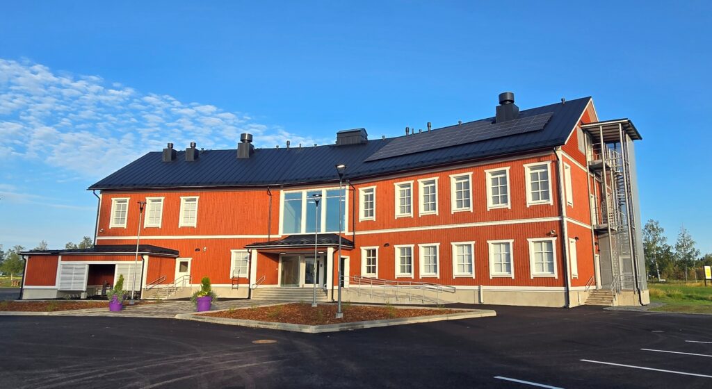Kolmikerroksinen, punainen pohjalaistyylinen puutalo kesäisessä alkuillassa.