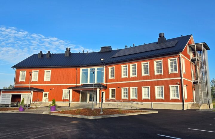 Kolmikerroksinen, punainen pohjalaistyylinen puutalo kesäisessä alkuillassa.